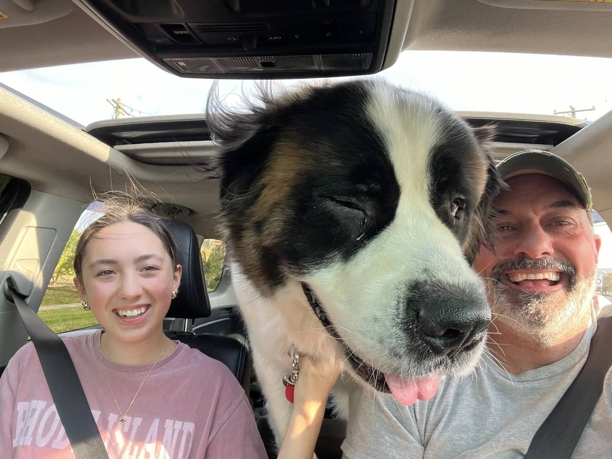 A relaxed family photograph inside a vehicle with Murphy the dog